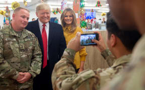 US President Donald Trump and First Lady Melania Trump take photos with members of the US military during an unannounced trip to Al Asad Air Base.