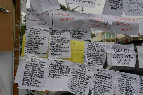 Lists of people and the hospitals they are in are posted near a school where at least 21 children died and 30 are missing.