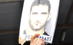 An asylum-seeker holds a picture of Reza Barati who died at the detention centre.