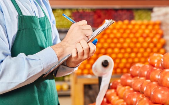 Businessman in the supermarket at inventory with checklist in the vegetable department