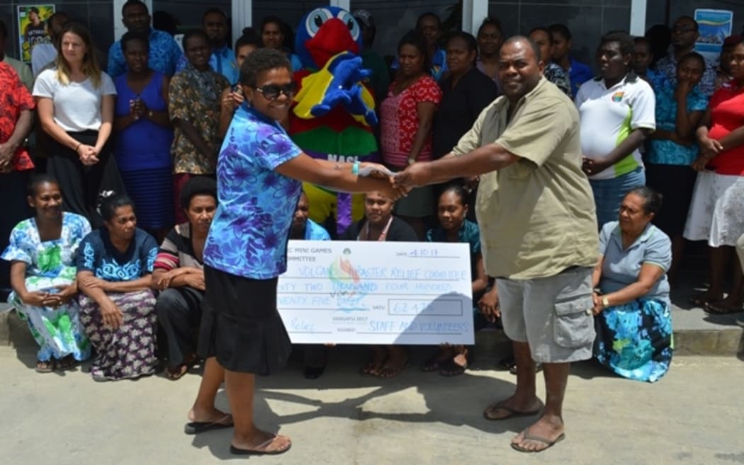Collin Michael from the Ambae Disaster Relief Committee in Port Vila receives a donation from the Mini Games Organising Committee.