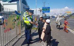 Young boys get autographs from police outside the Masjid e Umar Mosque in Auckland, where Prime Minister Jacinda Ardern spoke today.