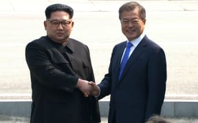 North Korea's leader Kim Jong Un (L) and South Korea's President Moon Jae-in shake hands at the Military Demarcation Line that divides their countries at Panmunjom.