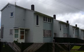 Row of two storey weatherboard houses with boarded up windows