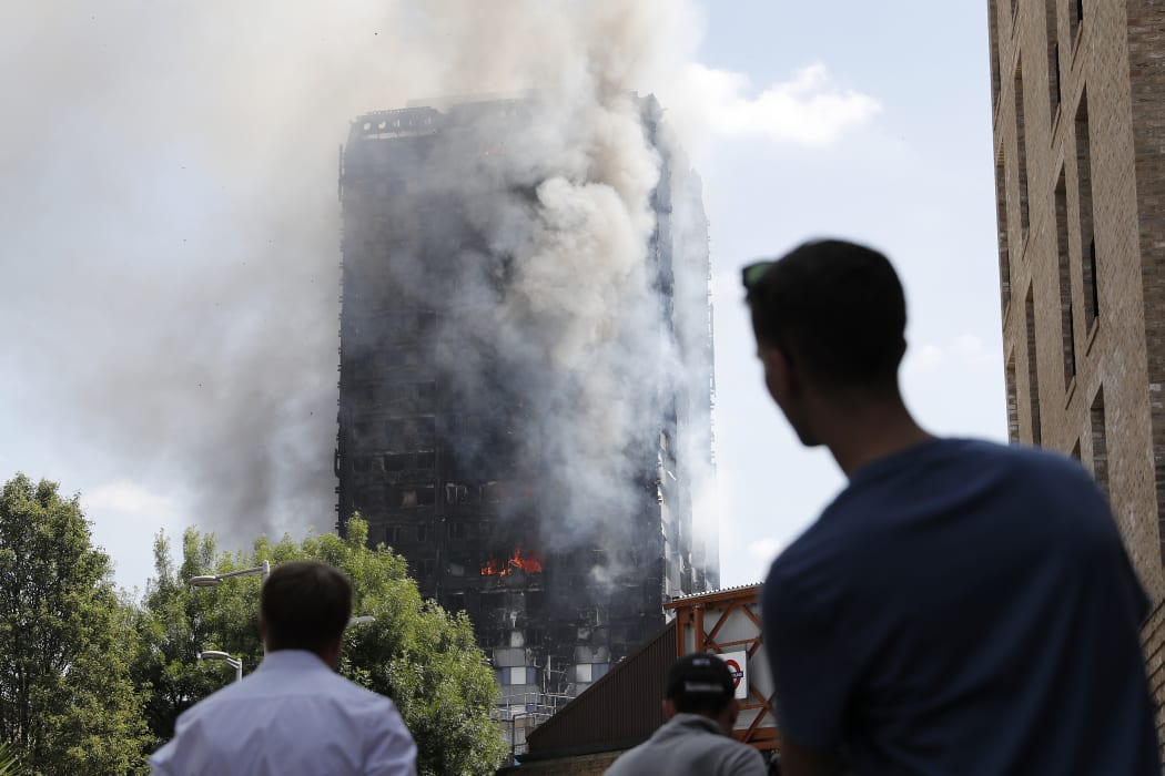 People look up towards Grenfell Tower as daylight revealed the 24-storey block still burning.