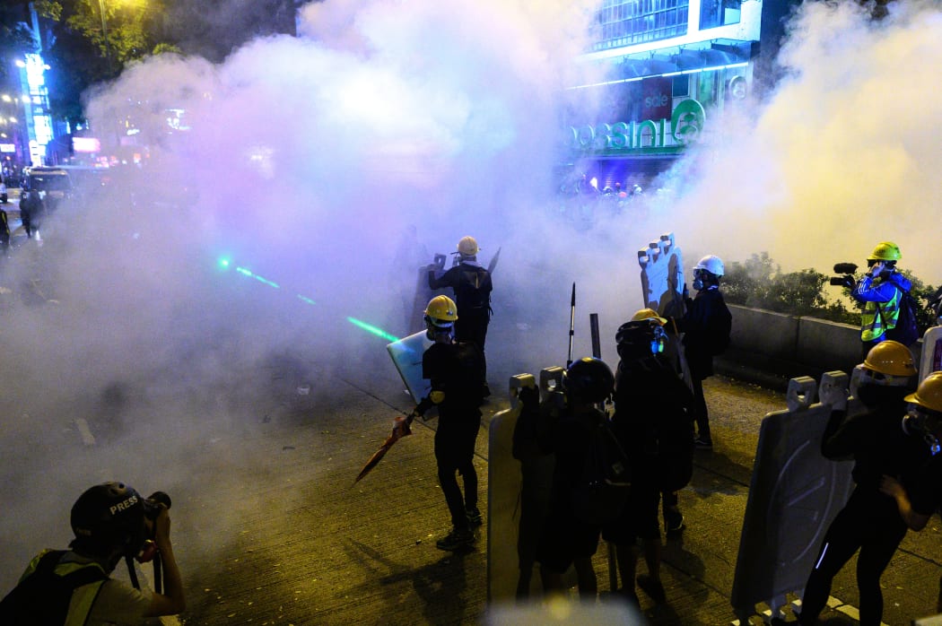 Protesters stand as police officers fire tear gas during a protest in Tsim Sha Tsui district of Hong Kong.