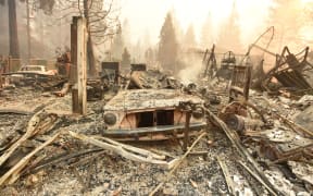 The burned remains of a vehicle and home are seen during the Camp fire in Paradise