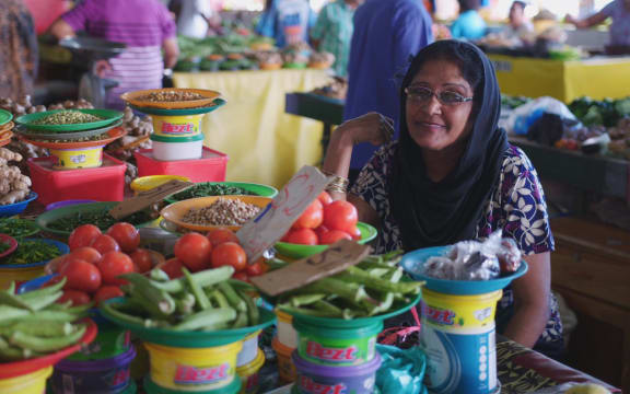 A Fijian Indian woman sits at her vibrant food stall at Suva Market