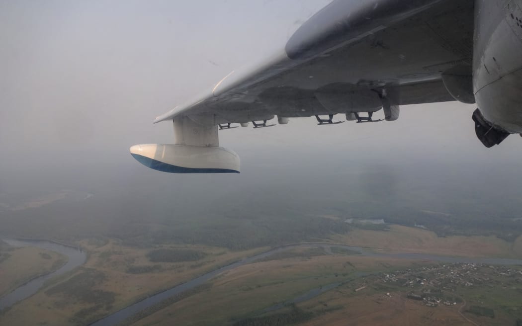 This handout picture taken on July 30, 2019 from onboard a Be-200 firefighting aircraft and provided by the press-service of Russia's Krasnoyarsk Krai's forestry ministry shows smoke from forest fires filling the sky over the Boguchansky district.