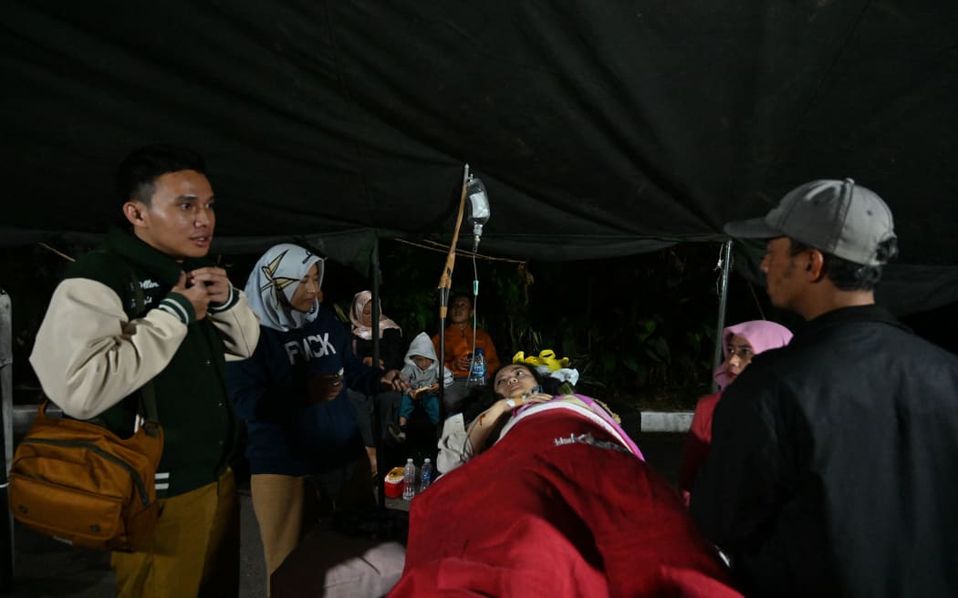 Injured people rest under a tent outside a hospital, following an earthquake in Cianjur on 21 November 2022.