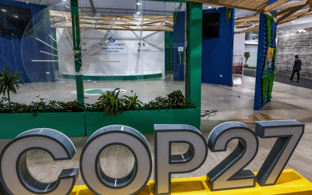 Une personne passe devant la conférence sur le climat COP27 dans la salle déserte du Centre international de conférences de Charm el-Cheikh, dans la station balnéaire égyptienne du même nom sur la mer Rouge, vers la fin de la conférence sur le climat le 19 novembre 2022 (Photo par Ahmed Gharabli/AFP )