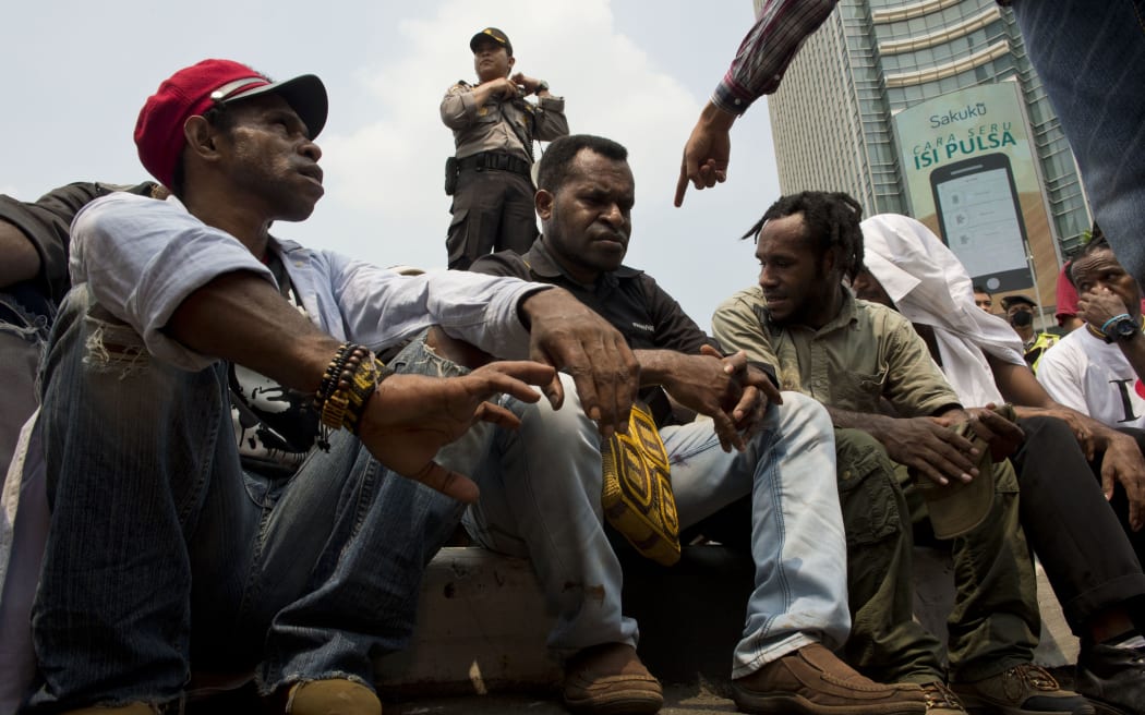 Papuan pro-independence demonstrators are arrested by police in Jakarta on December 1, 2015, after police fired tear gas at a hundreds-strong crowd hurling rocks during a protest against Indonesian rule over the eastern region of Papua.