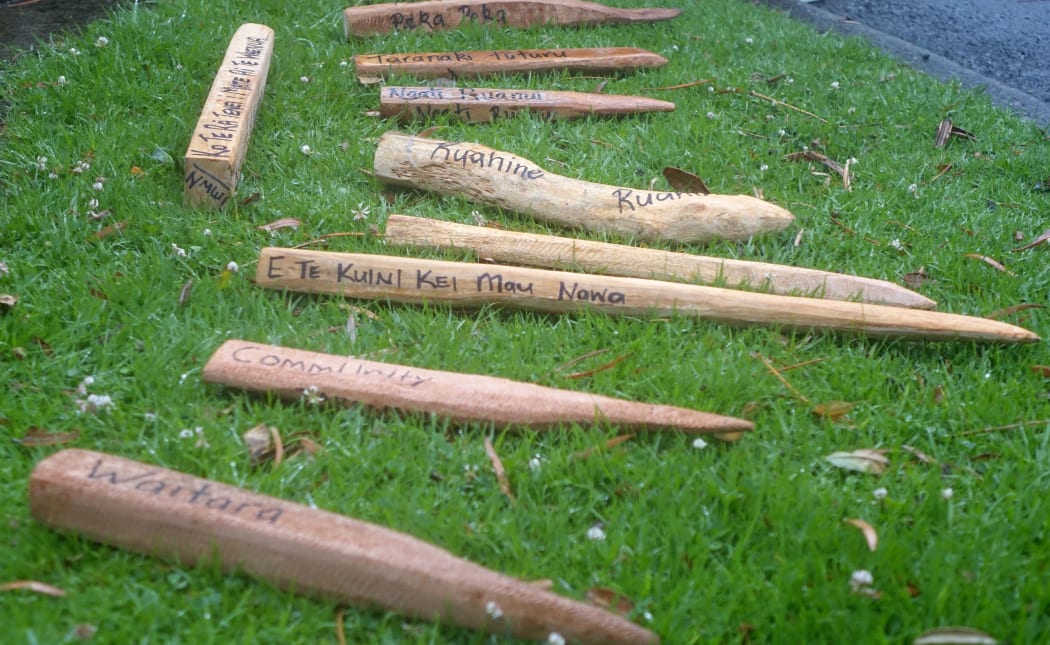 Roughly fashioned survey pegs with place names lie in the grass