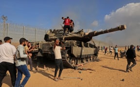 Palestinians take control of an Israeli tank after crossing the border fence with Israel from Khan Yunis in the southern Gaza Strip.