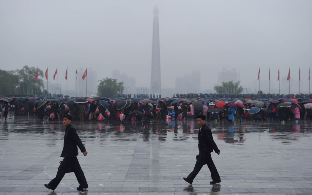A crowd of people are seen on Kim Il-Sung Square before the Juche tower as rain falls in Pyongyang.