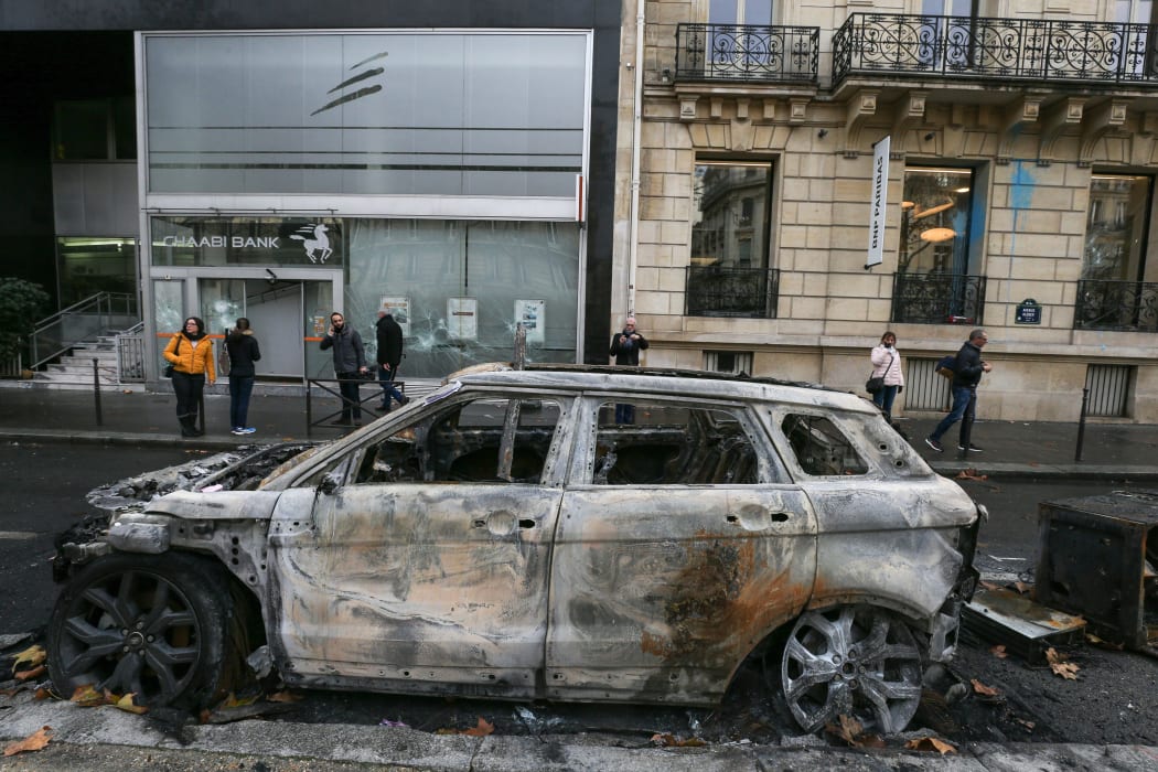 A burned car in front of a BNP Paribas bank branch vandalized in Kleber avenue in Paris.