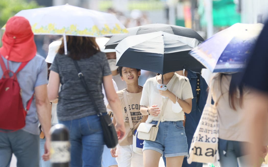 People walk in strong sunshine in Kyoto on July 4, 2023.