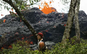 A lava fissure erupts as a resident stands nearby