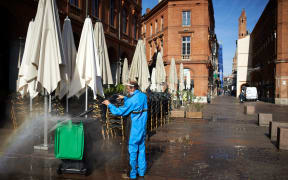 A worker cleans a bin in front of a closed cafe in Toulouse, on the second day of France's new lockdown.