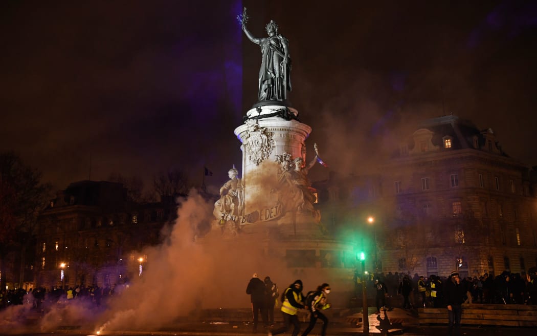 Smoke of tear gas is seen as protestors, including some wearing a yellow vest (gilet jaune), gather on Place de la Republique (Republic's Square) in Paris