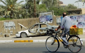 A cyclist passing by a burnt-out car a few days after Blackwater guards escorting US embassy officials opened fire in the Baghdad neighbourhood on 16 September 2007.