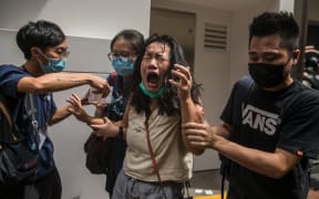 A woman reacts after she was hit with pepper spray deployed by police as they cleared a street where protesters were rallying against a new national security law in Hong Kong on July 1, 2020.