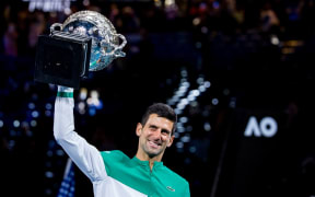 Novak Djokovic of Serbia raises his trophy after winning the Men's Singles Final of the 2021 Australian Open.