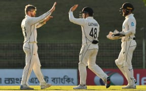 New Zealand’s Glenn Phillips, left, celebrates with Tom Latham, centre, after claiming a Bangladesh wicket in the first test in Sylhet.