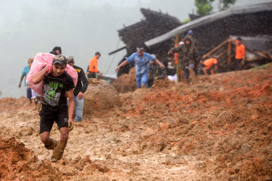 Residents evacuate their homes as rescue workers search for survivors at the site of a landslide triggered by heavy rain in Sukabumi, West Java province on January 1, 2019.