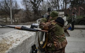 An Ukrainian serviceman looks through binoculars towards the town of Stoyanka at a checkpoint before the last bridge on the road that connects Stoyanka with Kyiv, on 6 March, 2022.