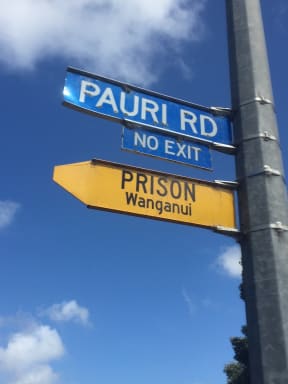 An image of a road sign pointing to Whanganui prison, with another sign beneath that reads "no exit."