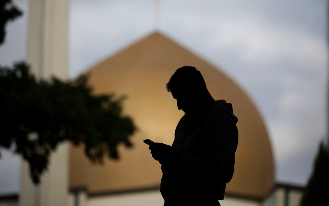 A member of the Muslim community uses his mobile phone out side the Al Noor mosque in Christchurch, New Zealand on March 15, 2020.