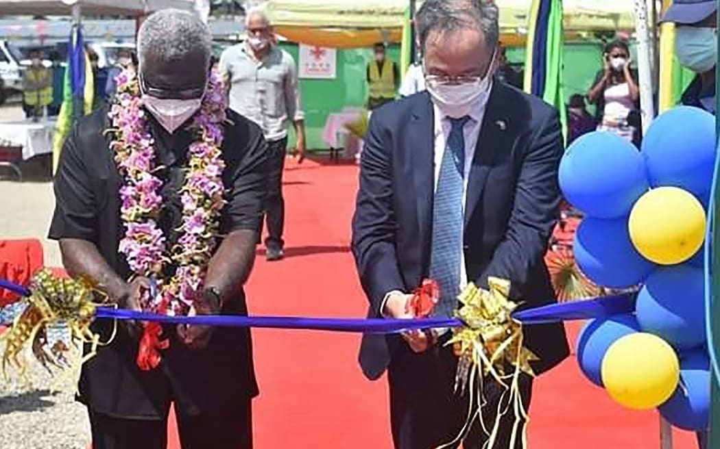 A photo taken on April 22, 2022 shows China's ambassador to the Solomon Islands Li Ming (R), and Solomons Prime Pinister Manasseh Sogavare (L) cutting a ribbon during the opening ceremony of a China-funded national stadium complex in Honiara. The stadium complex, reportedly worth 53 million USD, will host the 2023 Pacific Games for the first time in the island state of 800,000 people. (Photo by Mavis PODOKOLO / AFP)