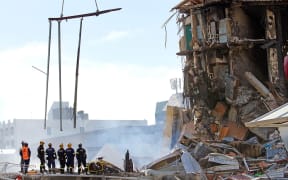Rescuers stand in the smoking ruins of the CTV building two days after the quake in 2011.
