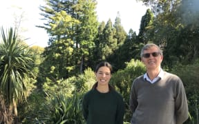 Hannah Rogers and Professor Bruce Clarkson at the top of Seely's Gully. Hannah and Bruce are standing in front of a lush green backdrop of plants and trees.