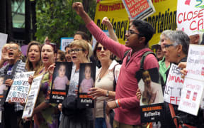 People hold up placards at a protest outside an immigration office in Sydney on February 4, 2016.
