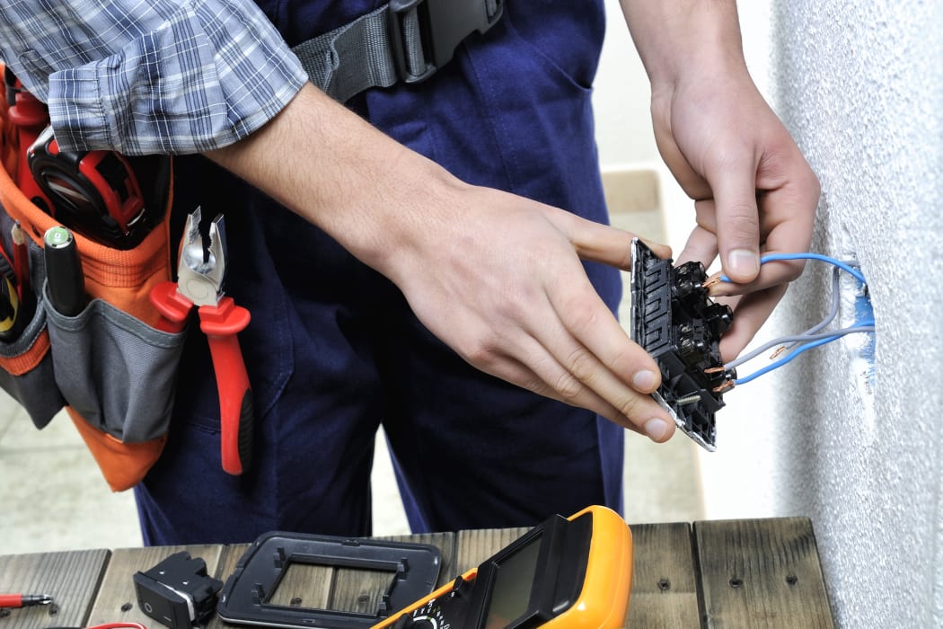 Young electrician at work on switches and sockets of a residential electrical installation.