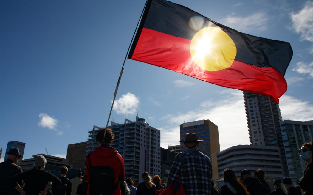 Se iza una bandera aborigen durante una protesta de Black Lives Matter para expresar solidaridad con los manifestantes estadounidenses y exigir el fin de las muertes de aborígenes bajo custodia, en Perth, el 13 de junio de 2020. (Foto de Trevor Collens/AFP)