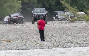 A protester from the Ashley Rakahuri Rivercare Group in Canterbury stands in front of 4WDs racing down the riverbed where endangered tarapiroe, black-fronted terns are nesting.