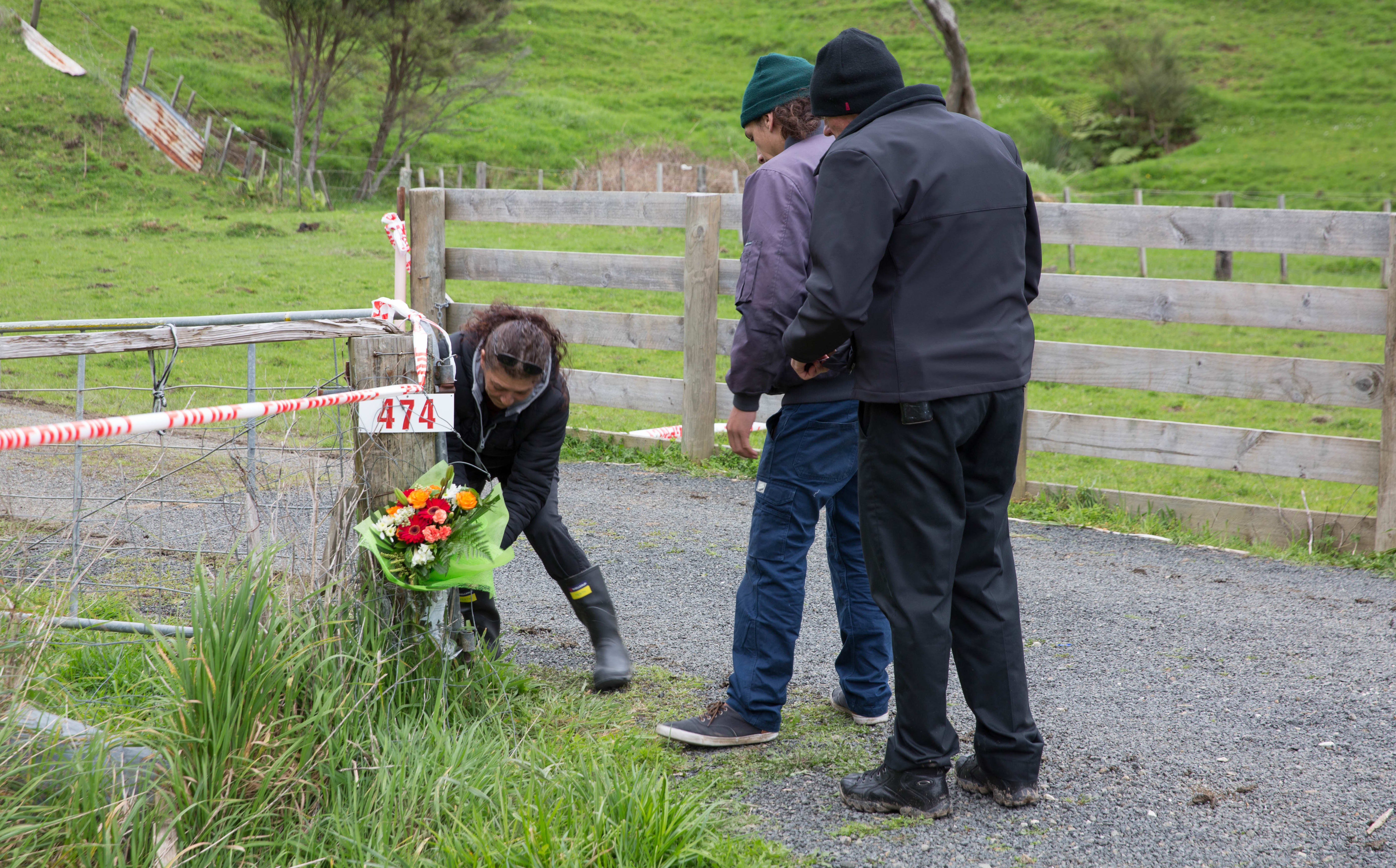 People place flowers at the entrance to the Kinohaku property where three bodies were found, including that of Ross Bremner.