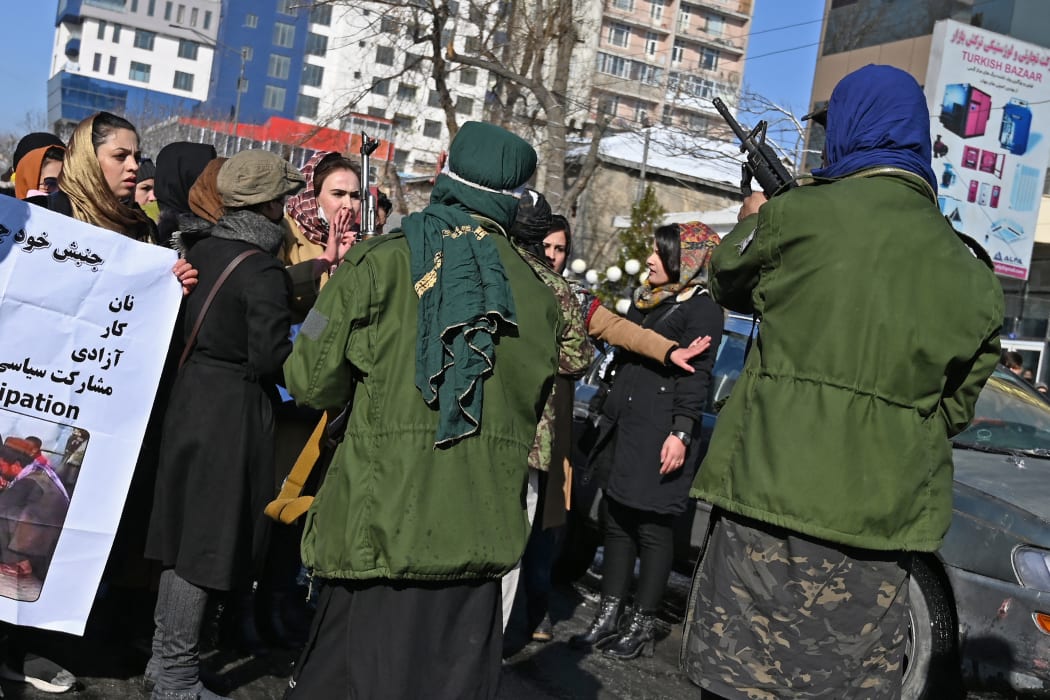 Taliban fighters trying to control women as they chant slogans during a protest demanding for equal rights, along a road in Kabul on 16 December, 2021.
