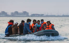 A Kuwaiti migrant, sits in a dinghy with his brother's family and other migrants as they illegally cross the English Channel from France to Britain on September 11, 2020.