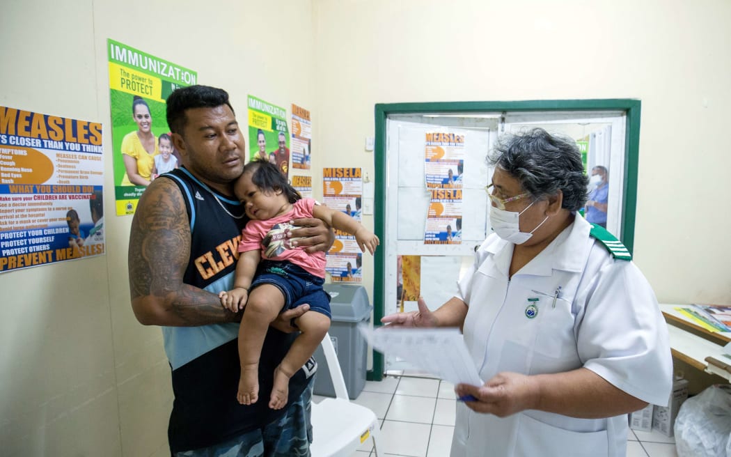 This picture released on December 5 by UNICEF Samoa shows nurse Fa'atafa Tavita (R) speaking with a family at the Apia Town Clinic in Samoa's capital city Apia.