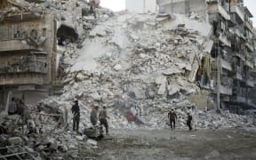 Members of the Syrian Civil Defence, known as the White Helmets, search for victims amid the rubble of a destroyed building following reported air strikes in the rebel-held Qatarji neighbourhood of the northern city of Aleppo, on October 17, 2016.