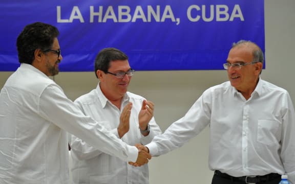 Colombian government head of delegation for peace talks Humberto de la Calle (R) and FARC-EP Commander Ivan Marquez (L) shake hands upon the signing of the agreement at the conclusion of the peace talks in Havana