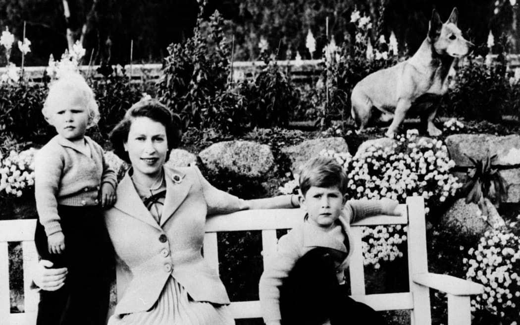 Undated handout photo of Queen Elizabeth II, her two children Charles (R) and Ann and a corgi posing at Balmoral.  (Photo by - /AFP)