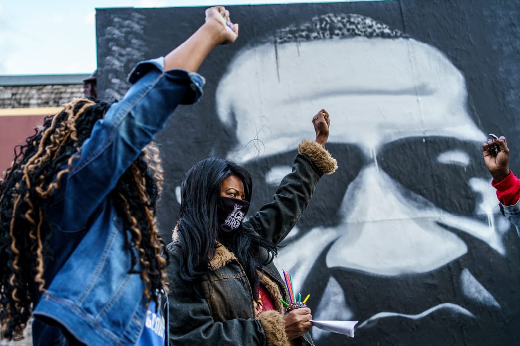 In this file photo taken on October 14, 2020 Paris Stevens (L) and Angela Harrelson (R), George Floyd's cousin and aunt, hold their fists as people gather in celebration of George Floyd's 47th birthday in Minneapoli.
