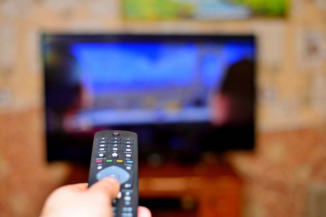 The man with the remote control in hand watching the sports channel and presses the button on the remote control. Remote control in hand closeup.