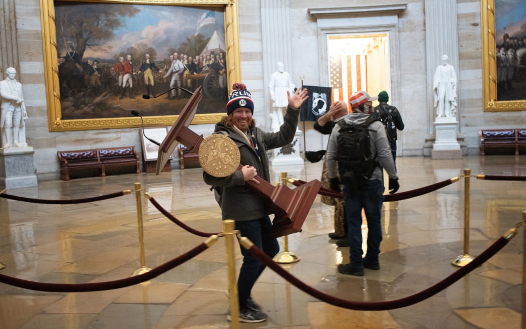 A pro-Trump protester carries the lectern of US Speaker of the House Nancy Pelosi through the Rotunda of the US Capitol Building after a pro-Trump mob stormed the building on January 06, 2021 in Washington, DC.