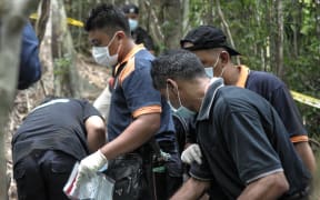 A Royal Malaysian Police forensics team handles exhumed human remains at a grave site near an abandoned migrant camp used by people-smugglers.